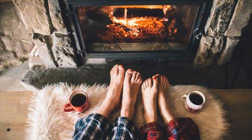 Couple staying warm by a fireplace